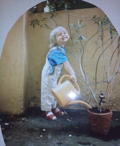 Louise as a toddler watering a plant